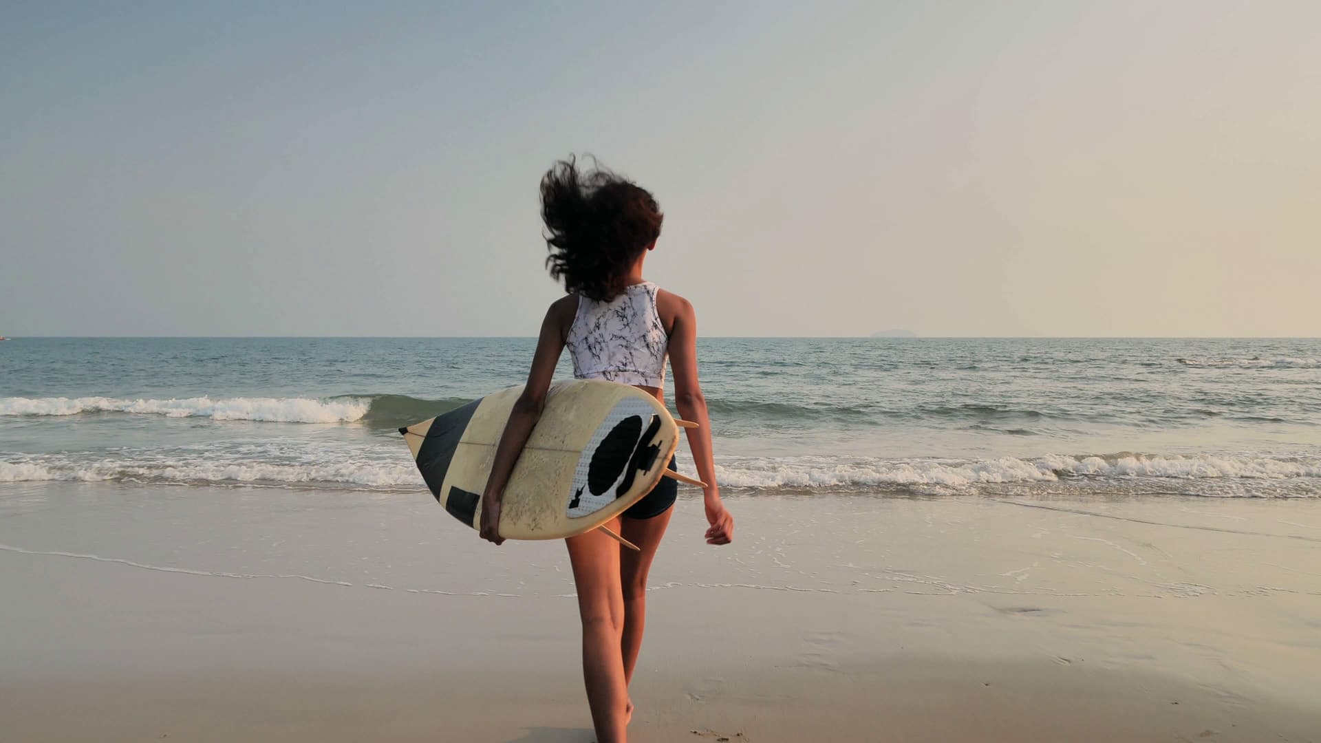 Surfer girl running into the ocean